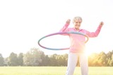 Senior woman doing gymnastic with hula hoop in park