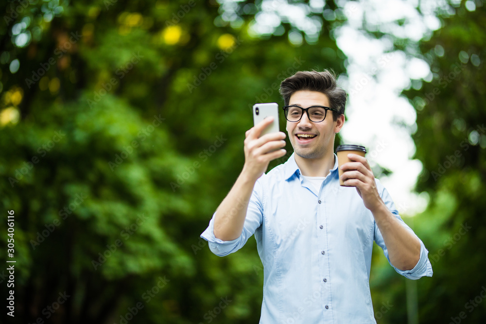 Young man wearing earpods holding and talking on smartphone while sitting in city cafe outdoors Young man wearing earpods holding and talking on smartphone while sitting in city cafe outdoors