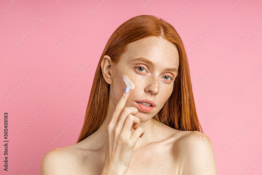 Beautiful young ginger woman with cream on face