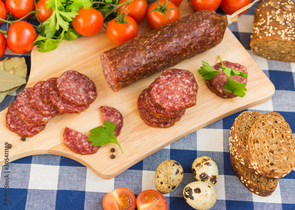 Sliced salami with bread, cherry tomatoes and quail eggs on table Sliced salami with bread, cherry tomatoes and quail eggs on table