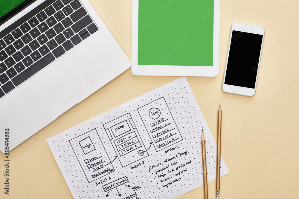 Obraz premium top view of gadgets near website design template and notebook with adaptive design lettering on yellow background