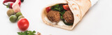 close up view of vegetables arranged in round frame around falafel in pita on white background, panoramic shot