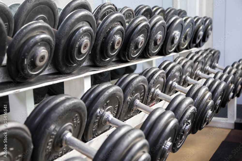 Set of heavy dumbbells on a horizontal support. Set of heavy dumbbells on a horizontal support.