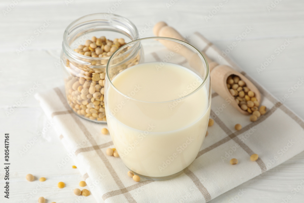 Glass of soy milk, soybeats seeds on white background, space for text. Closeup