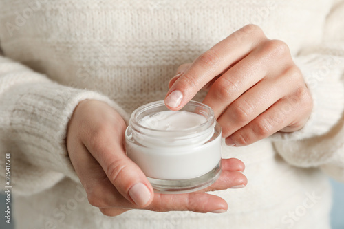 Woman holding jar of moisturizing cream  closeup. Winter cosmetic. Space for text