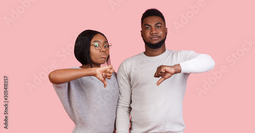 Afro couple showing thumb down gesture as rejection symbol