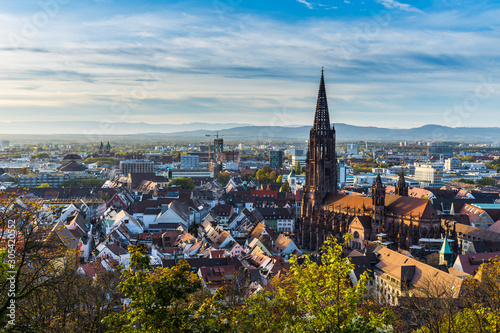 Germany, City freiburg im breisgau skyline with cathedral muenster in old town in warm sunset light in romantic autumn season, aerial view above cityscape