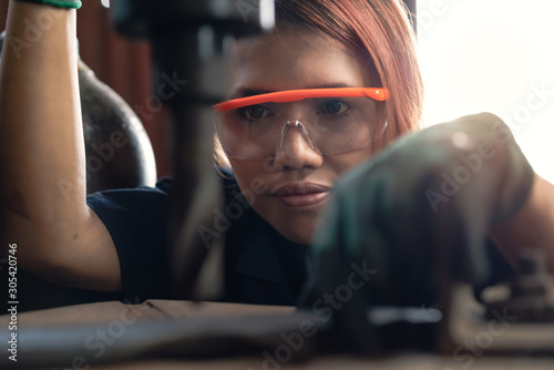 Diverse female certified industrial engineer operating factory drill machinery - Engineering student concentrating on production drilling for manufacturing business - Training and learning concept