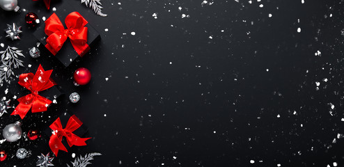 Merry Christmas and Happy Holidays greeting card, banner. New Year. Noel. Christmas red ornaments and gifts on black background top view. Winter xmas holiday theme.
