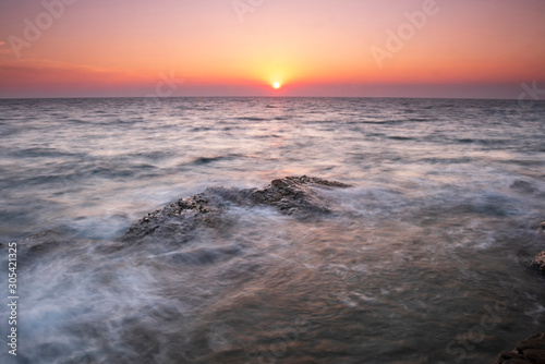 Beautiful seascape wave move on the rock at sunset