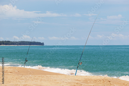Fishing rods on the sandy beach. Sea fishing on the tropical coast  colorful seascape