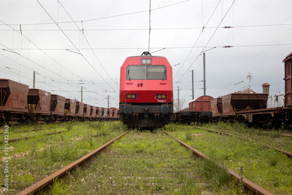 Red and black locomotive train in track surrounded by freight wagons. Symmetry. Transport