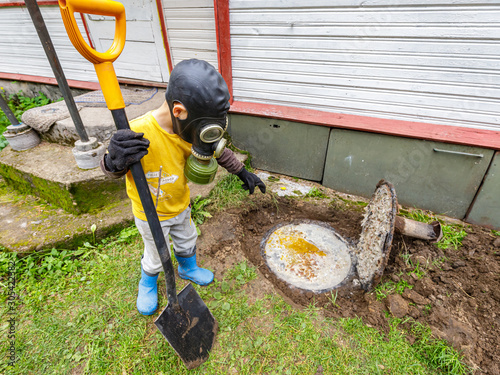 Problem with private filled septic. Boy in respirator and protective clothes trying to solve it.