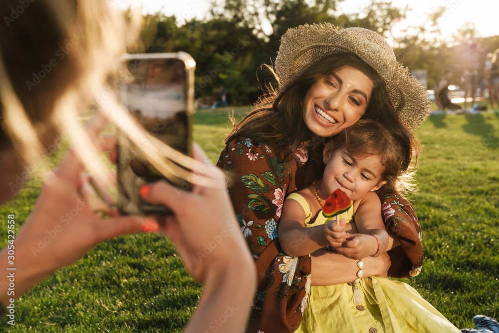 Fototapeta premium Someone take photo by mobile phone of woman and little daughter