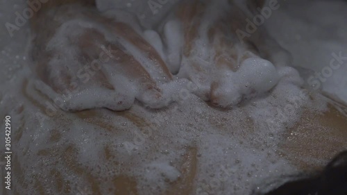  A woman lies in a Turkish bath-in a Hamam on a huge table on her stomach, a man massaging her back with the foams