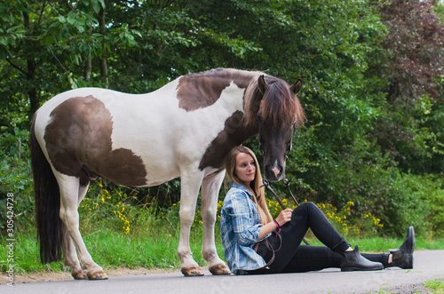 Reiterin sitzt auf einer Straße vor den Hufen ihres Ponys photo