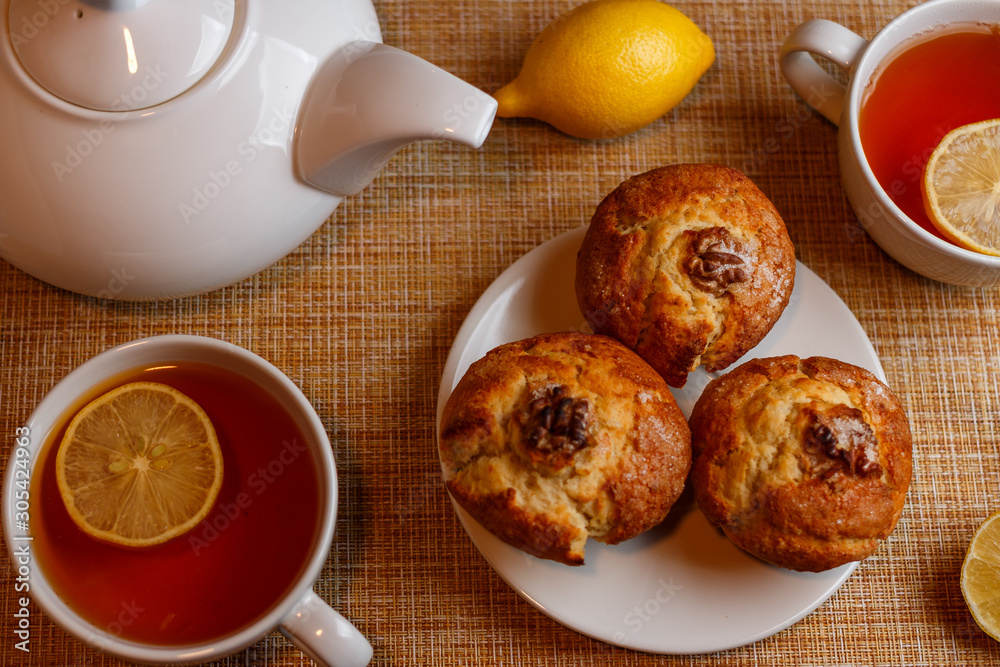 white teapot and two white cups of tea with lemon and muffins top view white teapot and two white cups of tea with lemon and muffins top view