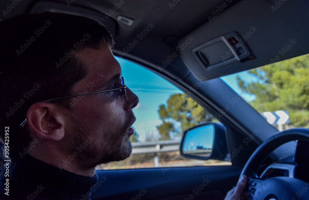 man driving looking at the road with sunglasses on a winter's day man driving looking at the road with sunglasses on a winter's day