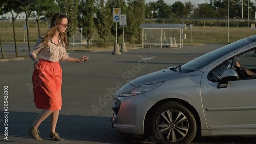 Beautiful caucasian girl walking down the street looking at her cell phone was almost hit by a car. Concept - smartphone addiction.