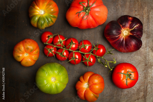Variedad de tomates sobre tabla oscura insaturada. Vista superior photo