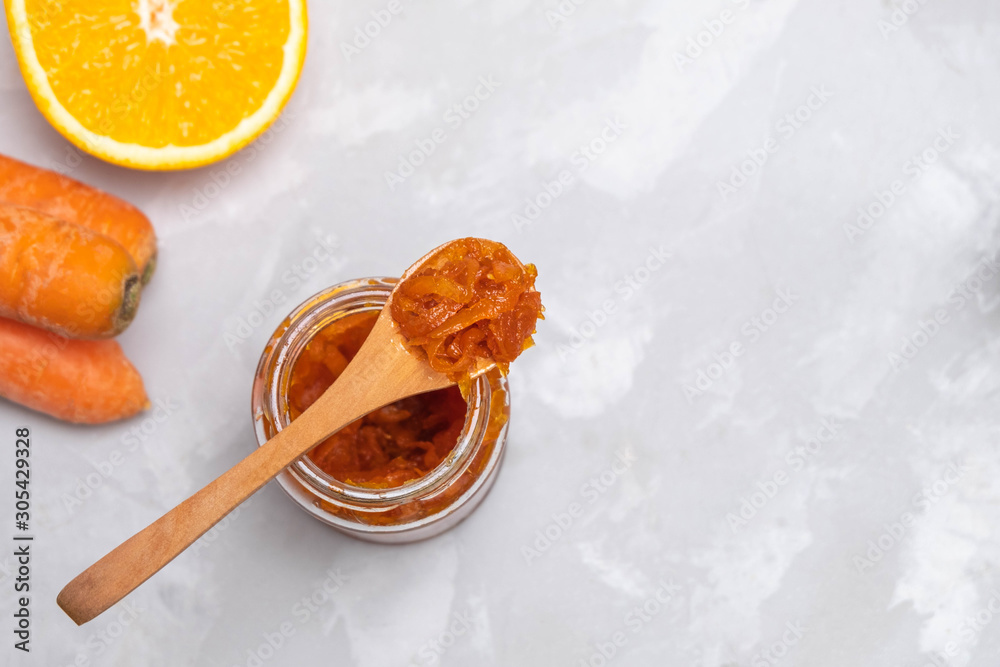 Fototapeta premium Jar of carrot jam made of sugar, carrots and oranges on concrete kitchen table
