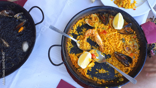 Paella marinera - traditional Spanish dish, paella, rice with seafood in a black pan on the table.