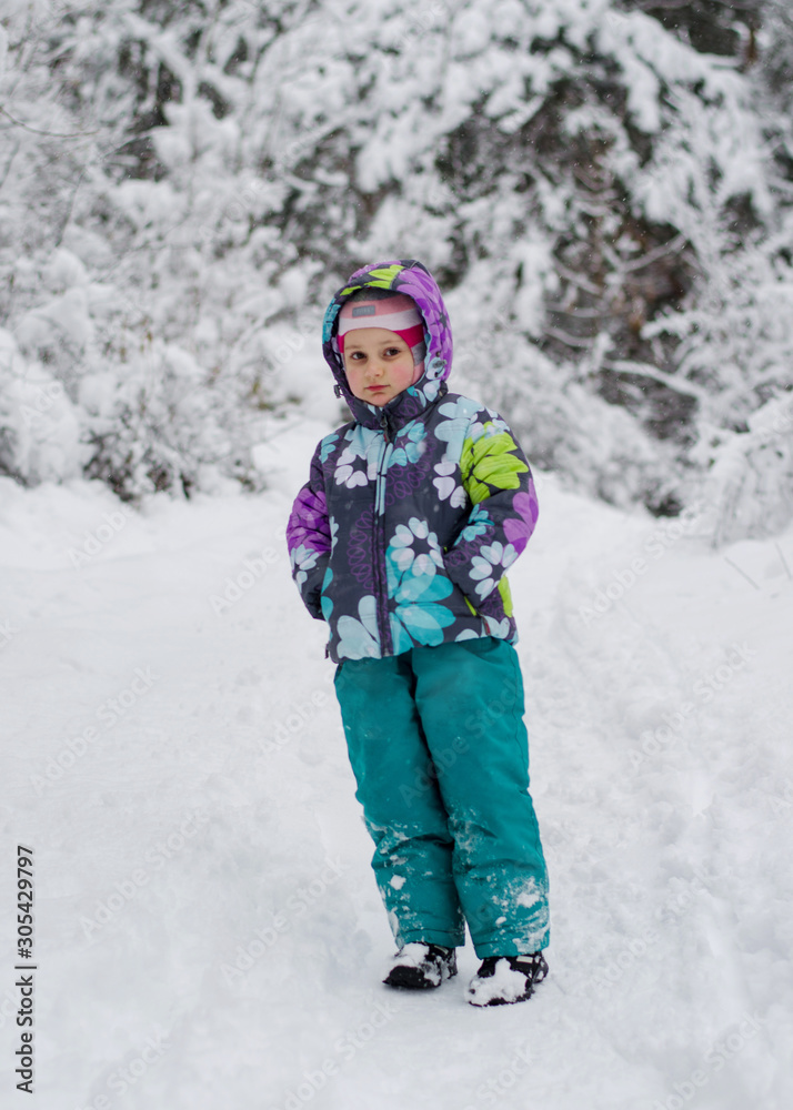 A child in the winter forest throws snow and laughs