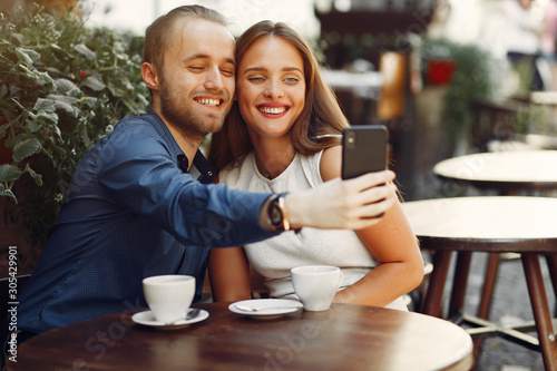 Male wih a phone. Man make a selfie. Lady in a white dress. Pair sitting on a cafe