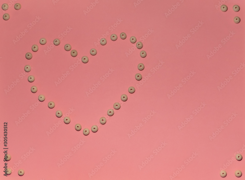 Composition for Valentine's Day February 14th. Big heart made of wooden beads on a delicate pink background. Greeting card. Flat lay, top view, copy space.