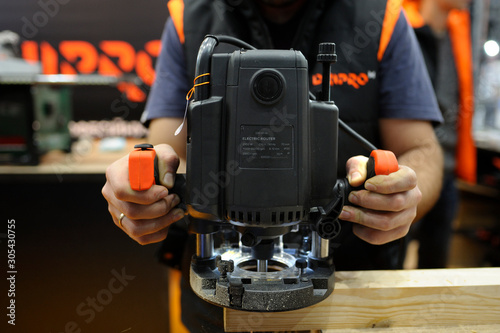 Worker hand hold the portable electric hand held woodworking router photo