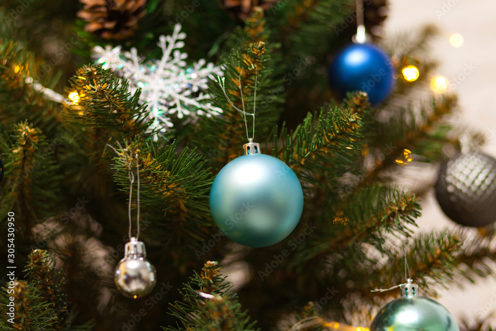 Fototapeta premium Beautiful green Christmas tree decorated with balls and garlands. Close-up photo