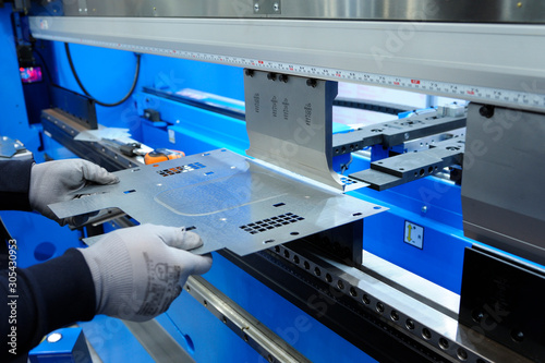 At the plant. Worker hold the metal sheet work with the CNC hydraulic press brake machine