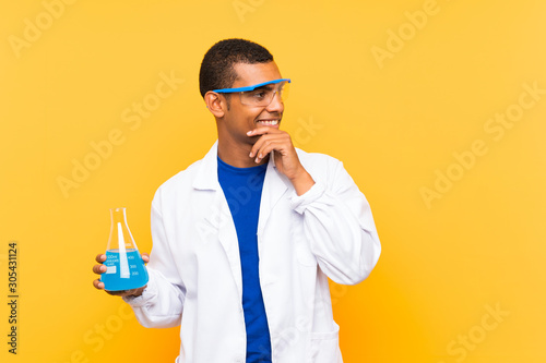 Scientific man holding a laboratory flask over isolated background thinking an idea and looking side