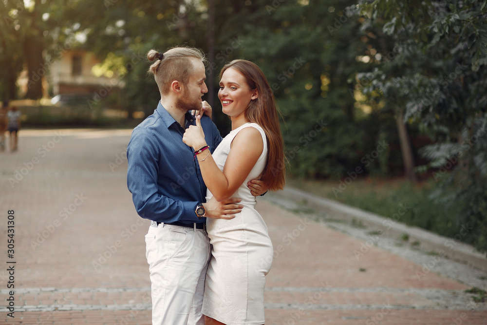 Cute couple in a park. Lady in a white dress. Man in a blue shirt