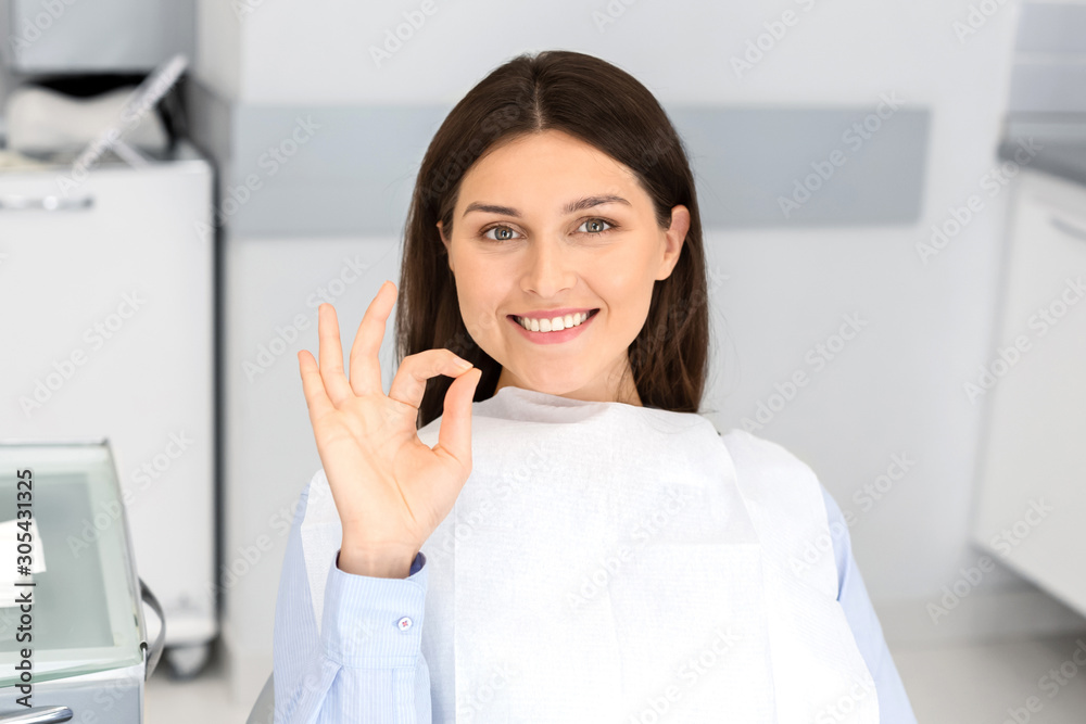Satisfied pretty parient in dentist chair showing okay Satisfied pretty parient in dentist chair showing okay
