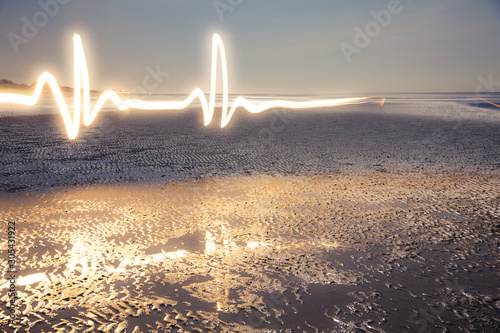 Light Painting Art: Luminous lifeline painted with a flashlight at the blue hour on the beach at low tide photo