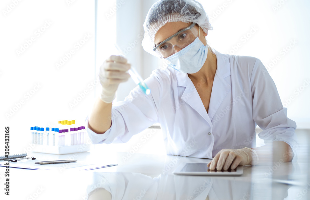 Professional female scientist in protective eyeglasses researching tube with reagents in laboratory. Concepts of medicine and research Professional female scientist in protective eyeglasses researching tube with reagents in laboratory. Concepts of medicine and research