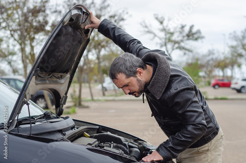 фотографія worried mature man looking under the hood of breakdown car