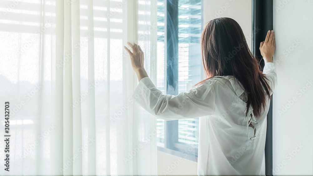 Asian woman opening window blinds after get up in morning sunrise. Morning lifestyle concept. Asian woman opening window blinds after get up in morning sunrise. Morning lifestyle concept.