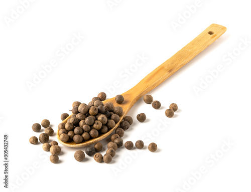 Dried allspice in a spoon on a white background