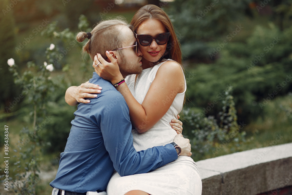 Cute couple in a park. Lady in a white dress. Man in a blue shirt Cute couple in a park. Lady in a white dress. Man in a blue shirt
