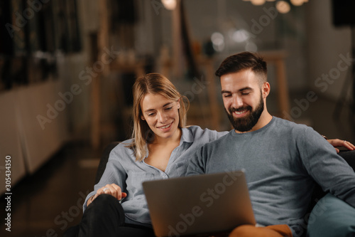 Young happy couple. Partners using laptop tohether. 