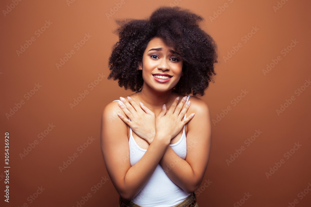 pretty young african american woman with curly hair posing cheerful gesturing on brown background, lifestyle people concept pretty young african american woman with curly hair posing cheerful gesturing on brown background, lifestyle people concept
