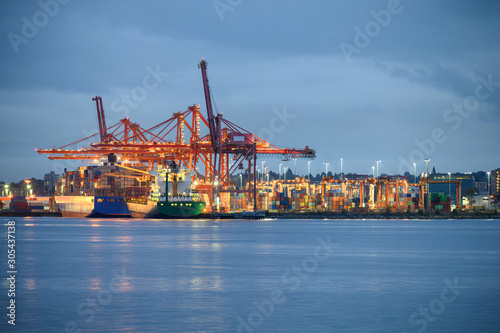 International cargo ship with containers cargo illumination and gantry cranes at port