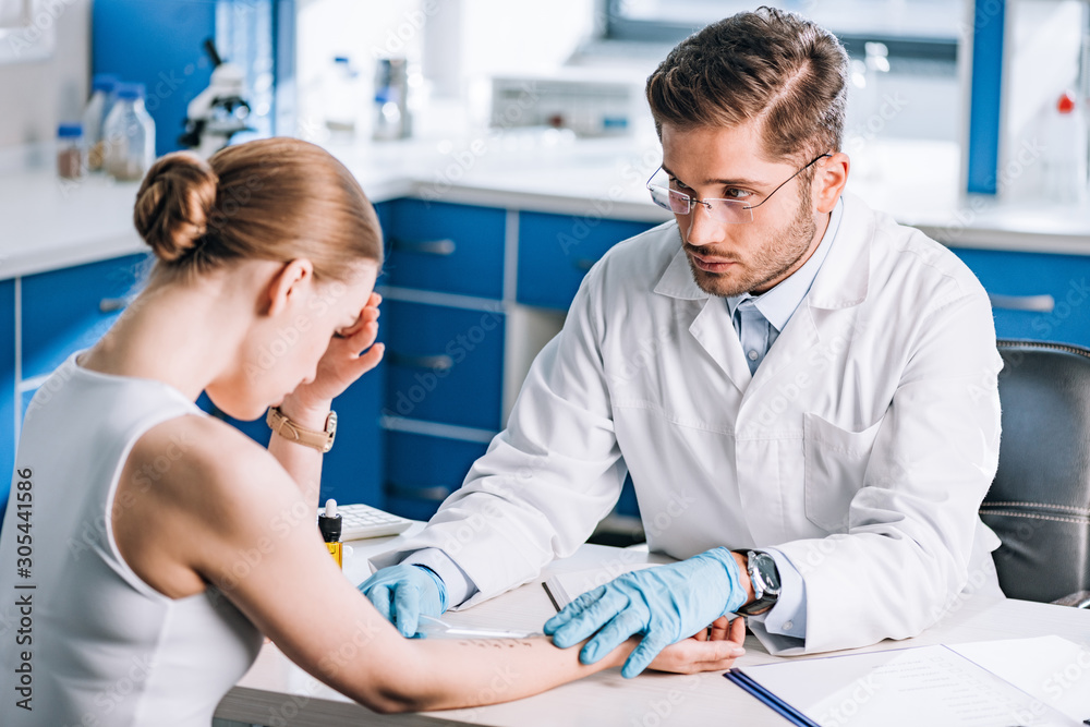 Obraz premium selective focus of handsome allergist holding ruler near marked hand of sad woman
