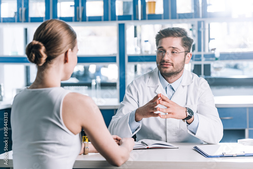 selective focus of handsome doctor in glasses looking at patient