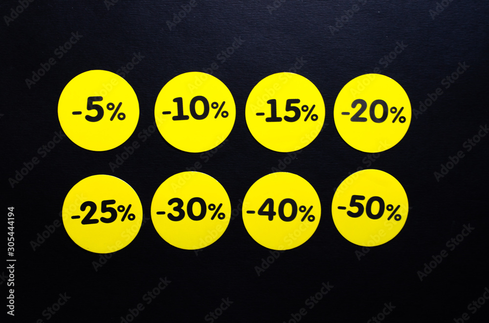 Yellow round stickers with discounts of 10 to 50 percent. Sell-out. Discounts on a black background. Black Friday. Price fall. Posters. Macro discounts. Yellow round stickers with discounts of 10 to 50 percent. Sell-out. Discounts on a black background. Black Friday. Price fall. Posters. Macro discounts.