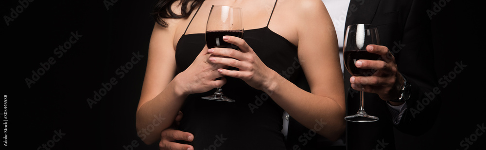 panoramic shot of man and woman holding glasses with red wine isolated on black panoramic shot of man and woman holding glasses with red wine isolated on black