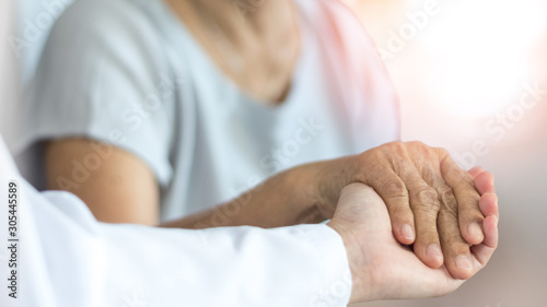 Elderly female hand holding hand of young caregiver at nursing home.Geriatric doctor or geriatrician concept. Doctor physician hand on happy elderly senior patient to comfort in hospital examination