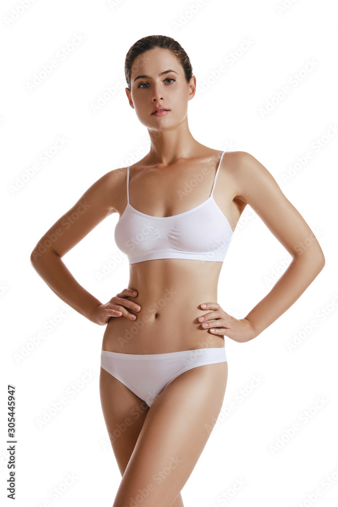 Young woman in white underwear, with bundled hair, hands on hips, posing isolated on white. Plastic surgery, aesthetic cosmetology. Close-up shot.